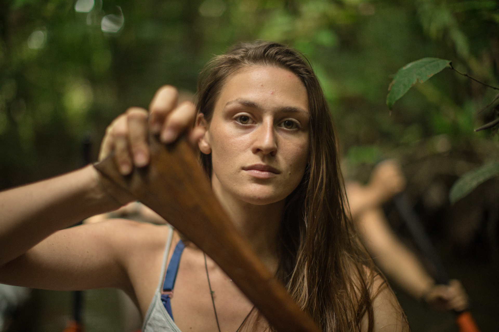 Laura Bingham holding a wooden paddle in the jungle. Photo by Peiman Zekavat.