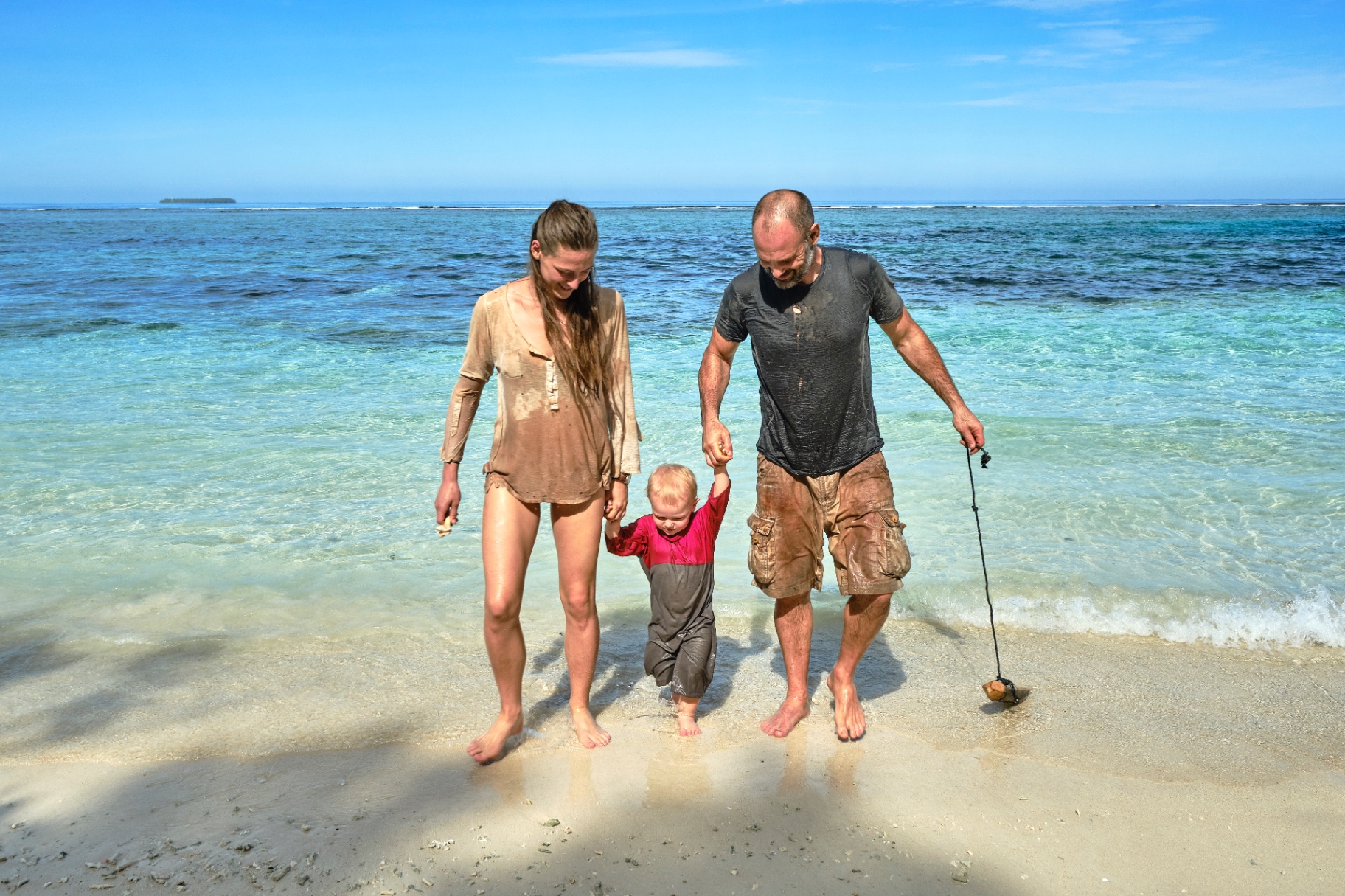 Laura, Ed and their son walking along a remote Indonesian beach