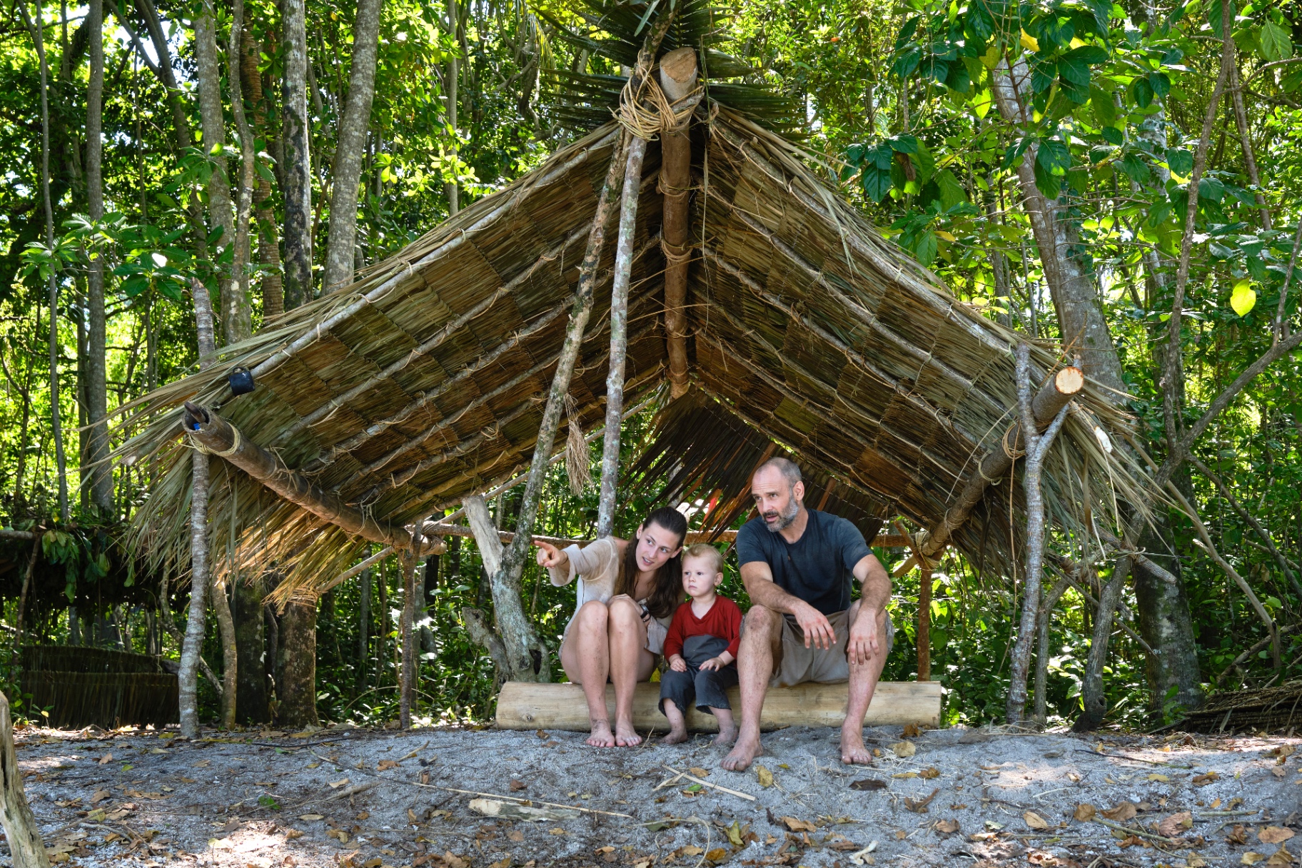 Laura, Ed and their son inside the palm-leaf shelter they built on the island