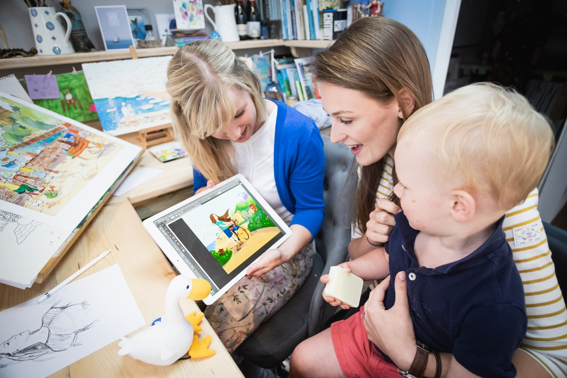Laura and illustrator Laura Wall reviewing artwork together with Laura's young son